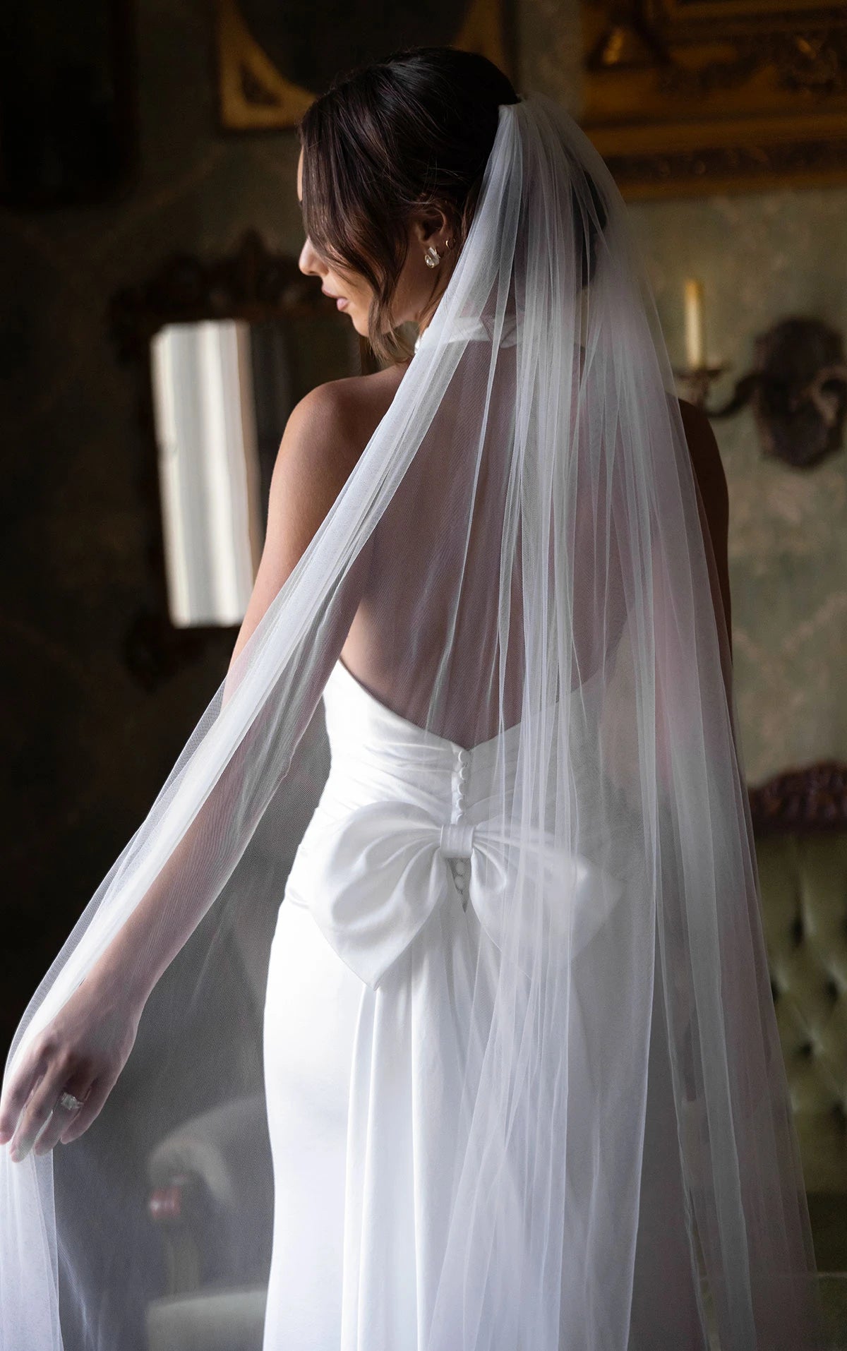 Bride in a white dress with a long veil in an elegant indoor setting.